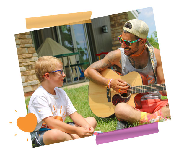 camper with counselor playing guitar